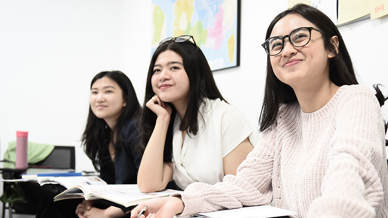 Tiga gadis duduk berjejeran, tersenyum melihat ke depan